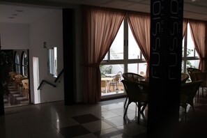 A hotel lobby with a staircase, large windows with curtains, and wicker furniture. - Santa Faz TRG (Benidorm)