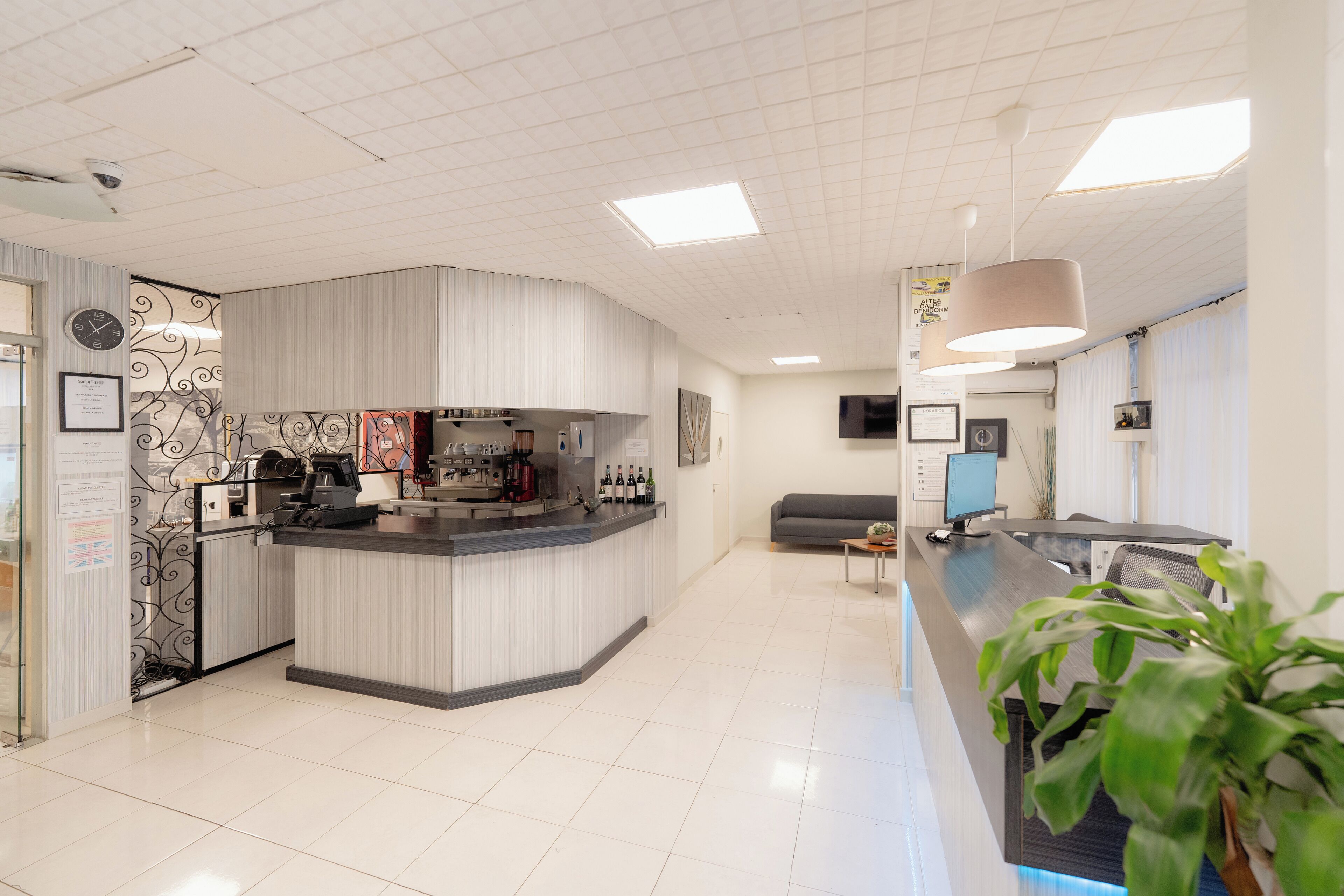 Un moderno vestíbulo de hotel con mostrador de recepción, zona de estar y cocina.