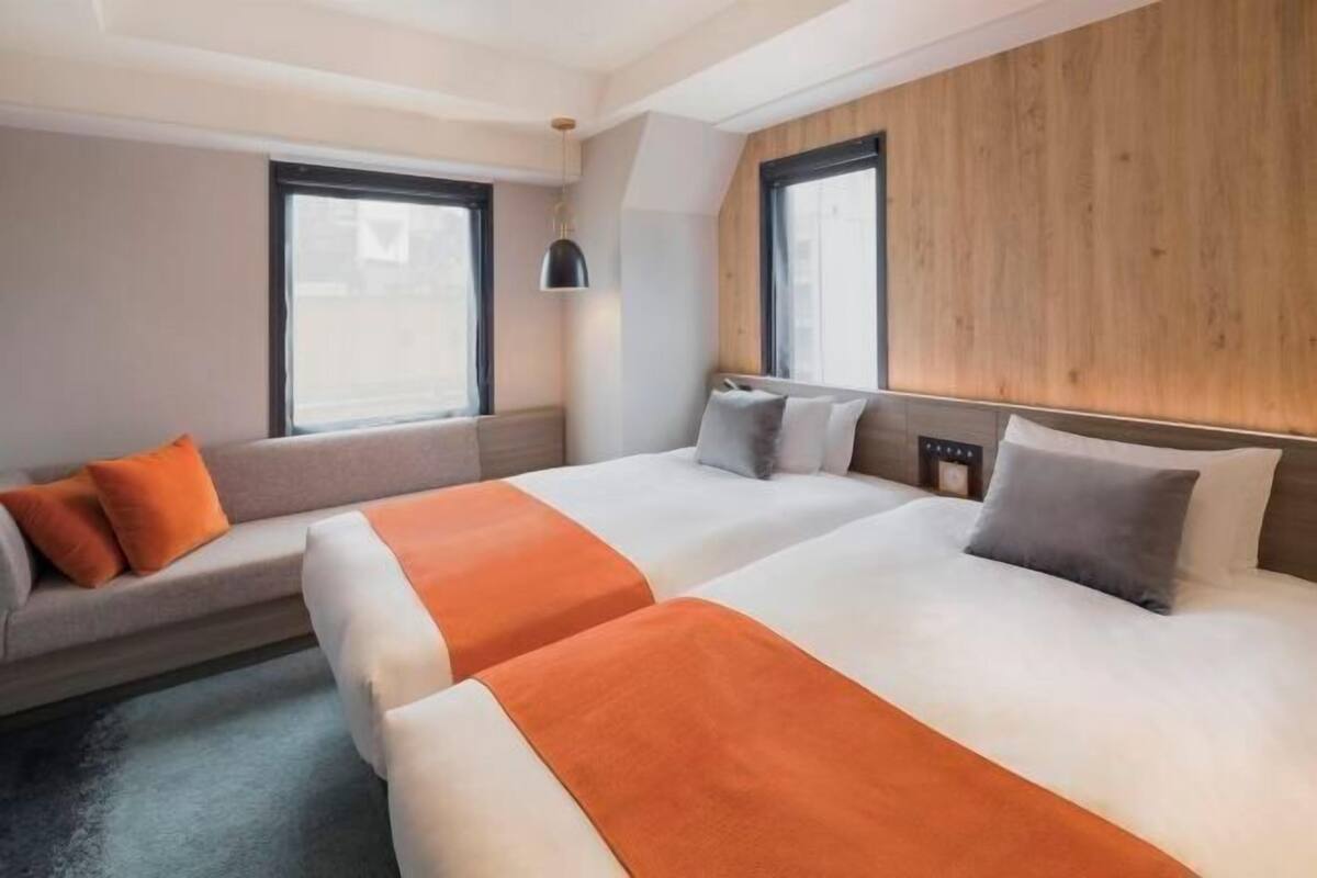 Habitación de hotel con dos camas, un sofá y una ventana.