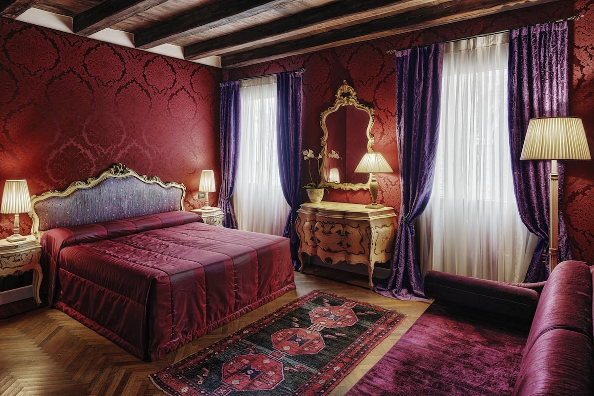 A room with a large bed, a dresser, a mirror, and two lamps.
