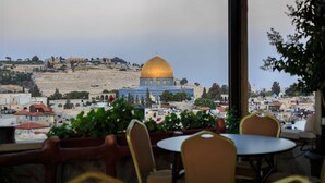 A view of the Dome of the Rock with surrounding buildings and a table with chairs in the foreground. - Hashimi Hotel (Jerusalem)