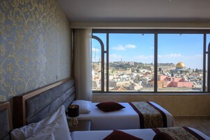 Habitación de hotel con un ventanal grande que ofrece vistas a un paisaje urbano y una cúpula destacada.
