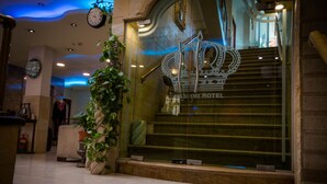 A hotel lobby with a staircase leading to the upper floors, a clock on the wall, and a decorative emblem above the entrance. - Hashimi Hotel (Jerusalem)