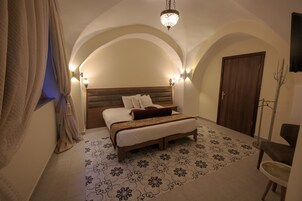 Un dormitorio con cama, candelabro, puerta de madera y suelo estampado.