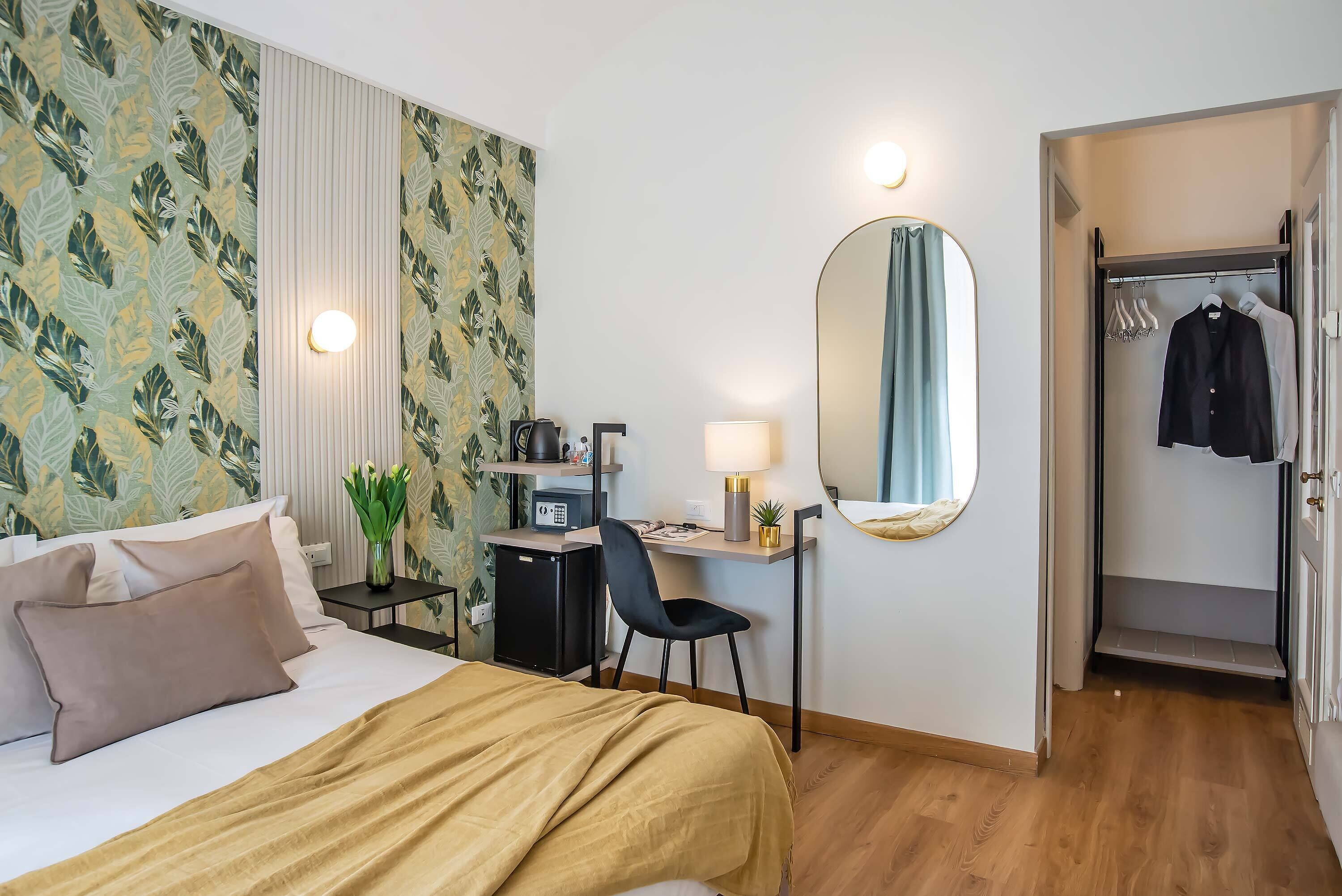 A hotel room with a bed, desk, chair, and a wardrobe.