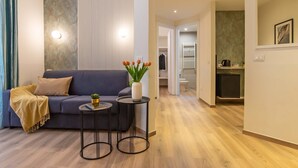 Een moderne woonkamer met een bank, twee bijzettafels en een potplant.