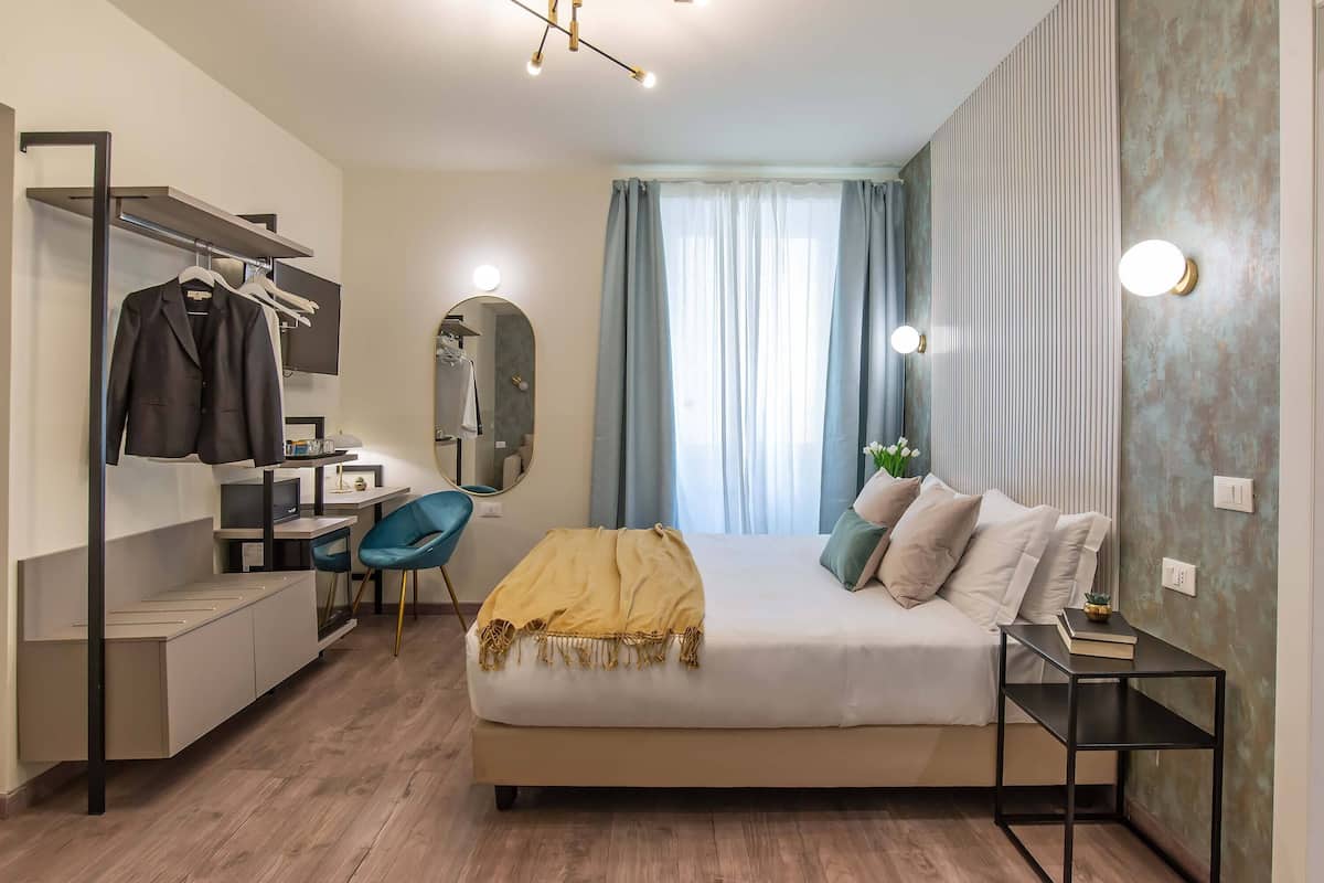 Een moderne slaapkamer met een bed, nachtkastje, bureau, stoel en kledingkast.