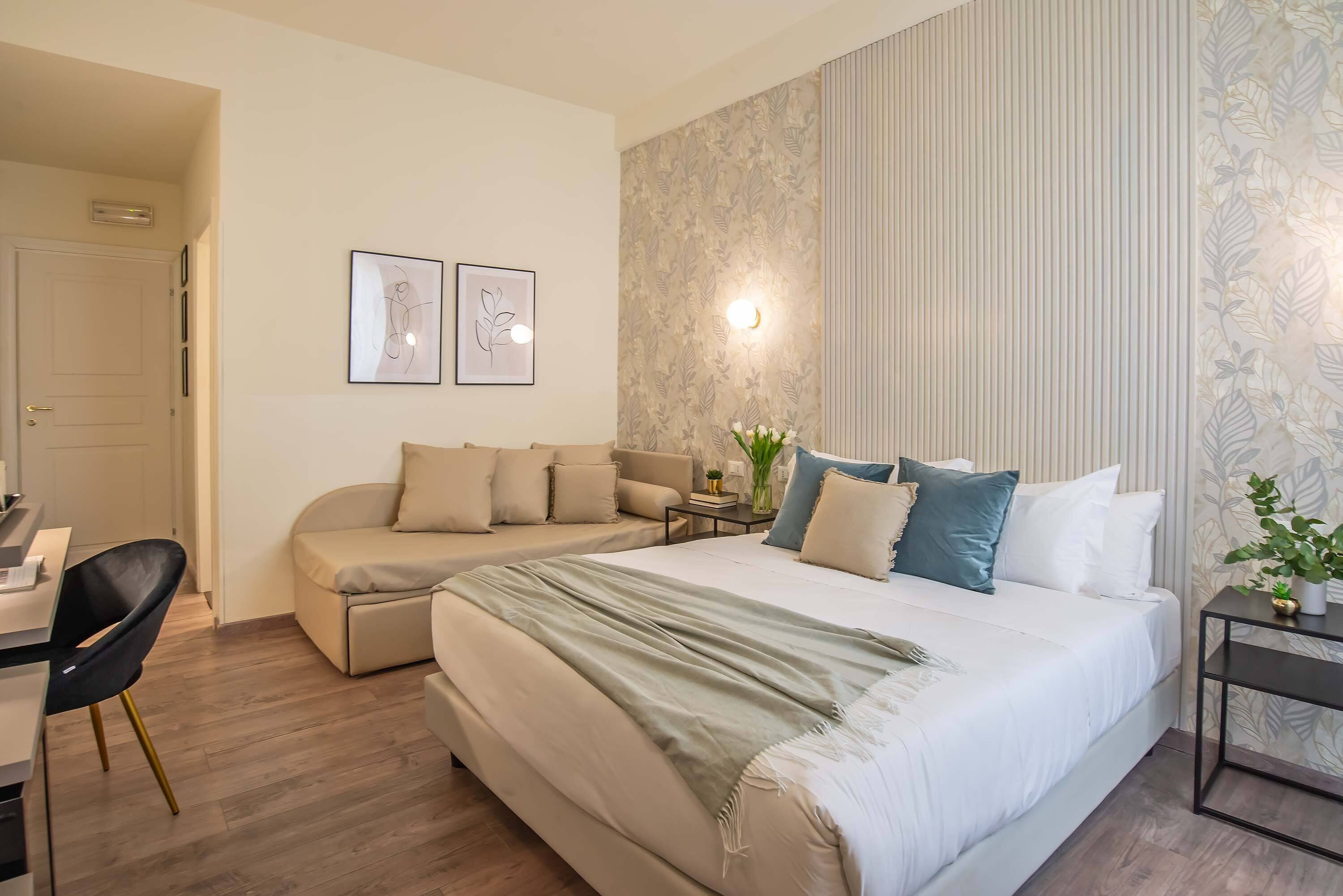 A bedroom with a bed, a sofa, a desk, and a chair.