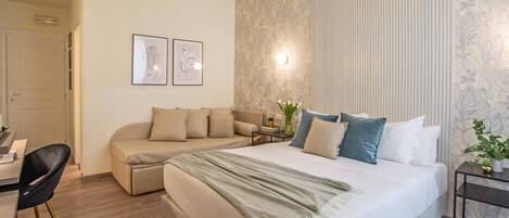 A bedroom with a bed, a sofa, a desk, and a chair.