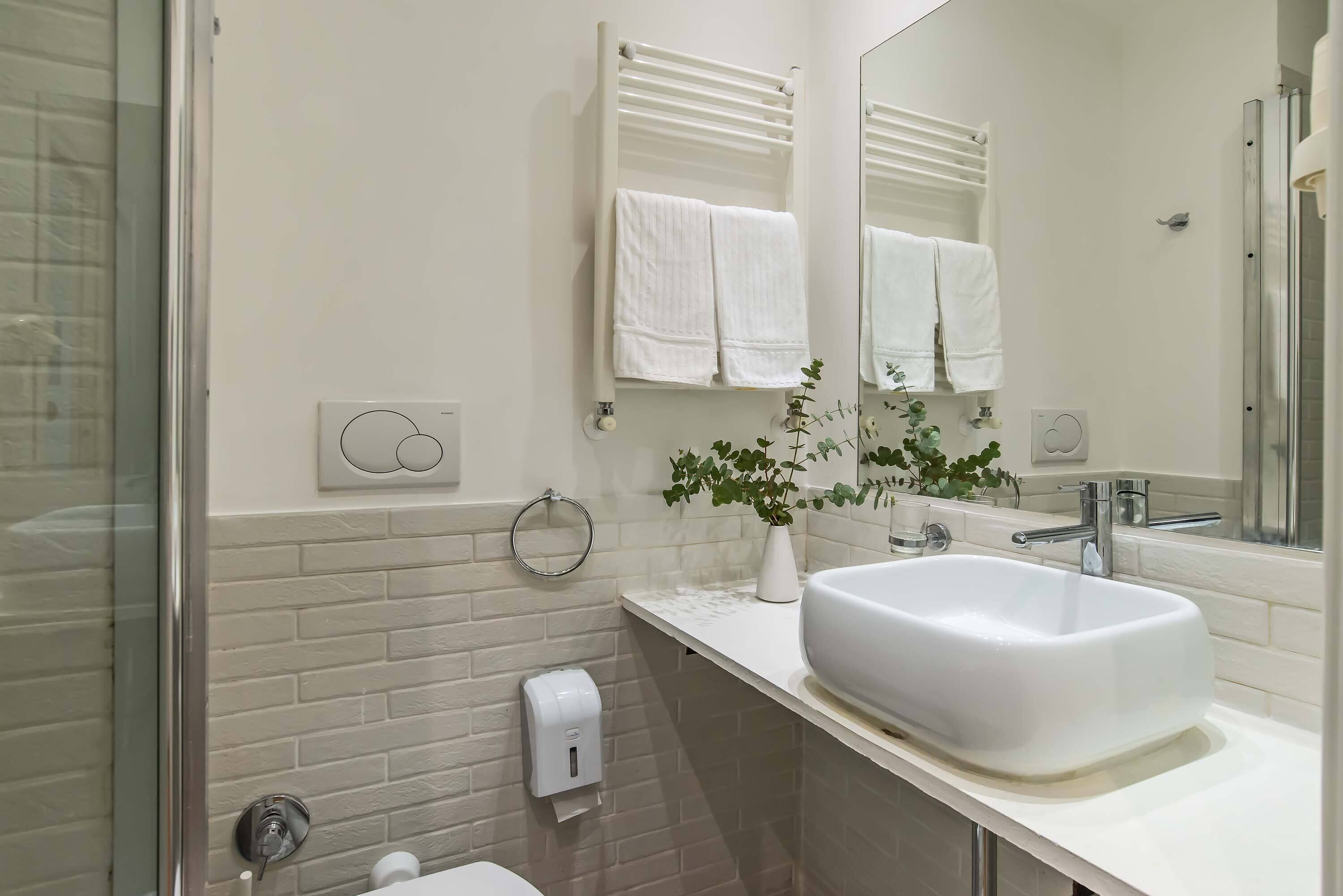 A modern bathroom with a white sink, a glass shower enclosure, and a mirror above the sink.