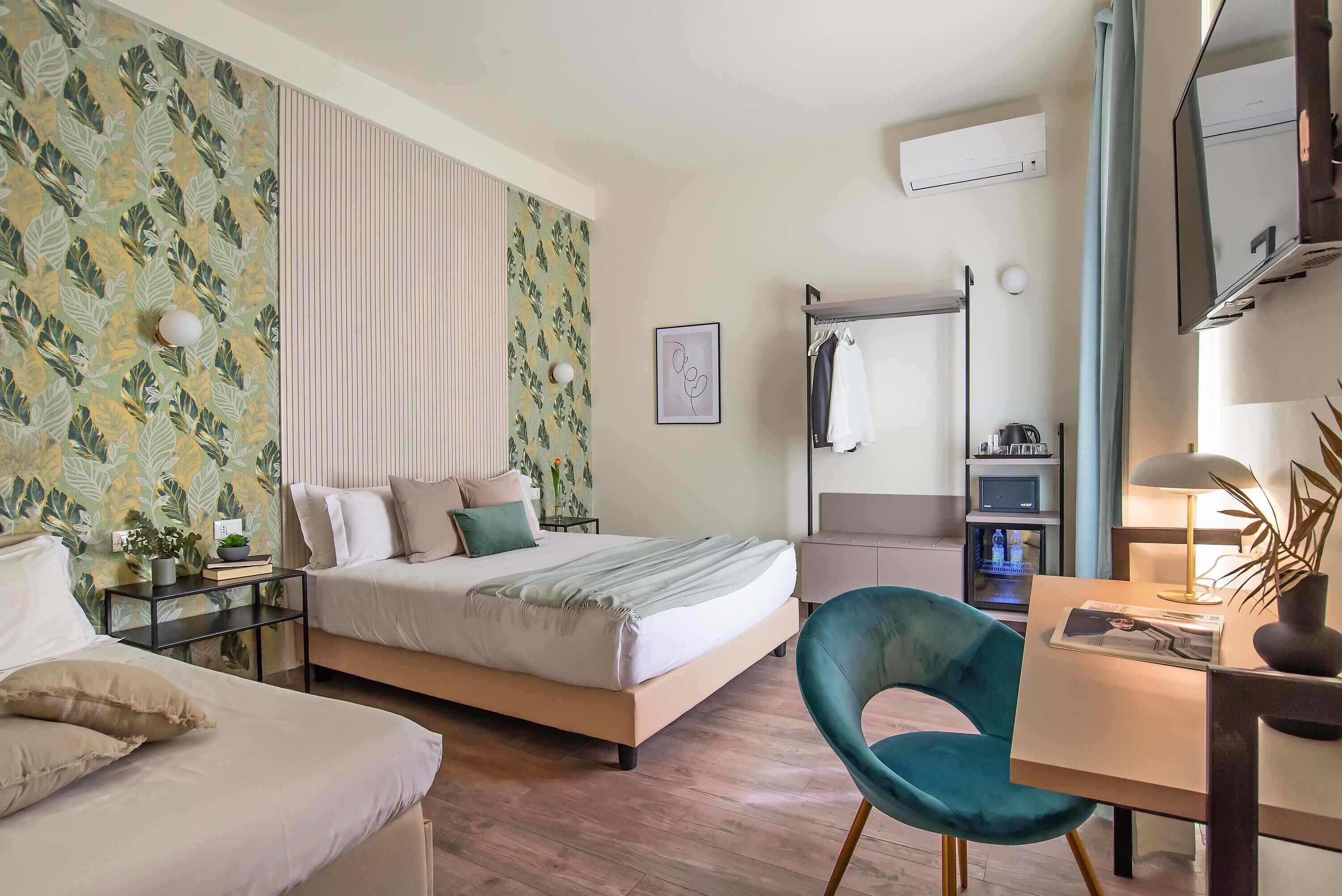 Una camera da letto con un letto, comodini, una scrivania con sedia, uno specchio e una TV a parete.