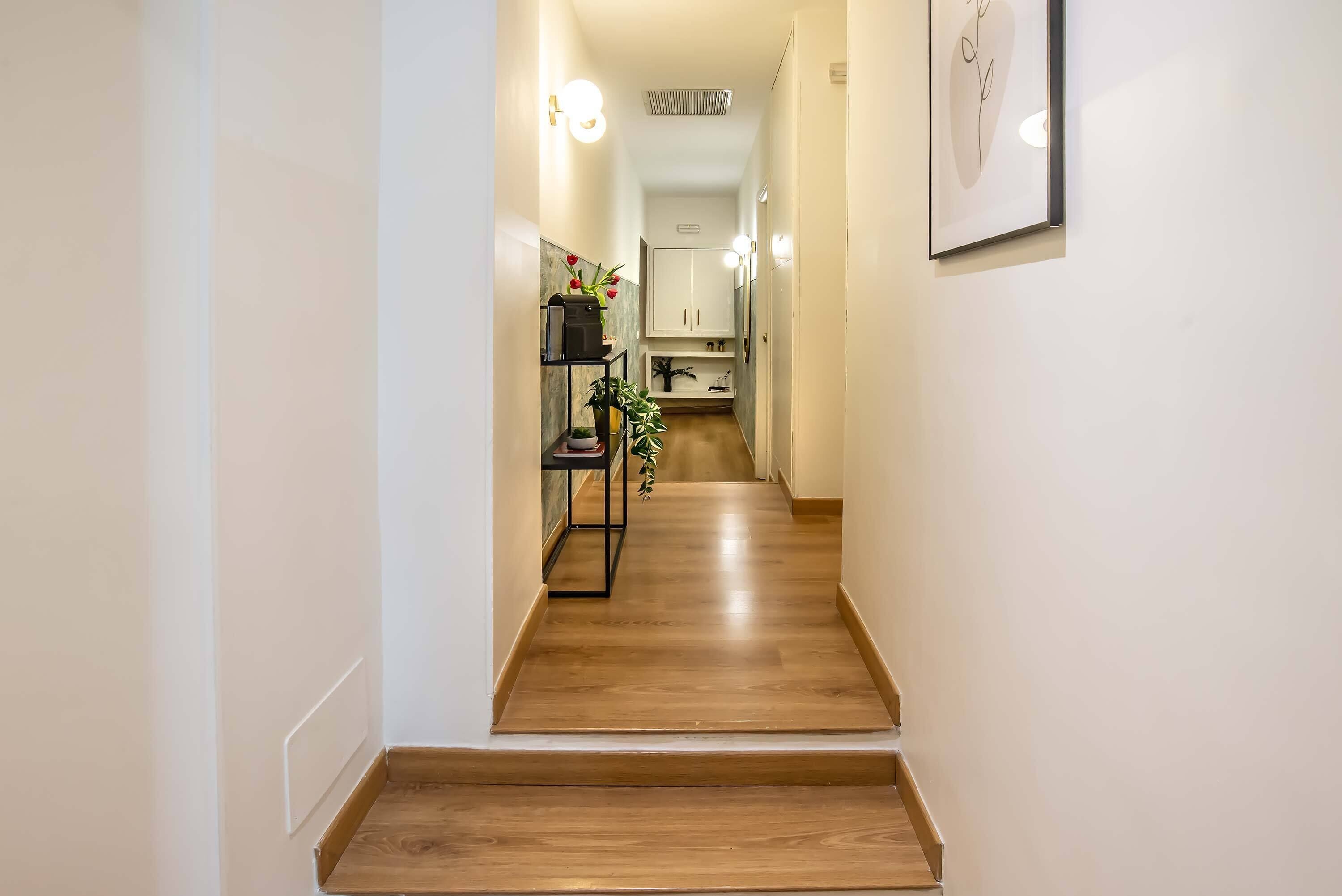 Un couloir étroit, doté d’un plancher en bois, mène à une cuisine.