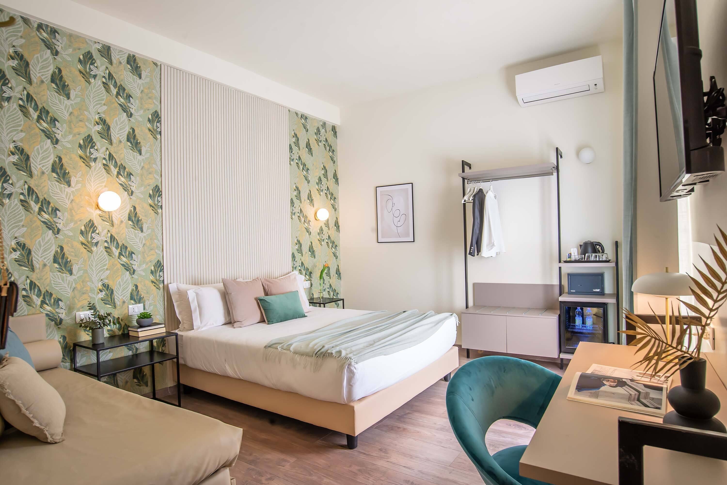A bedroom with a bed, bedside table, chair, and a desk with a lamp.