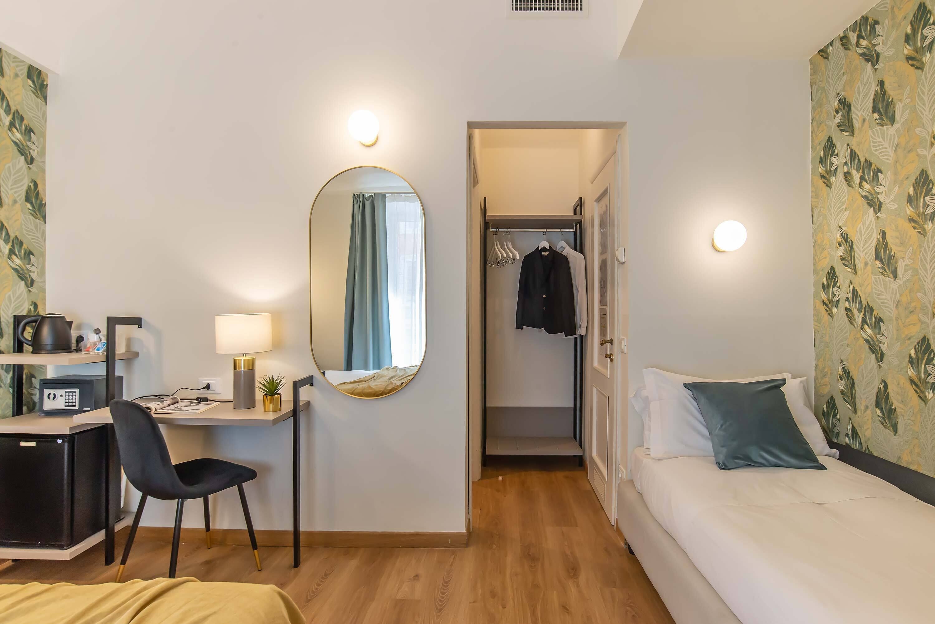 A hotel room with a desk, chair, bed, and a walk-in closet.