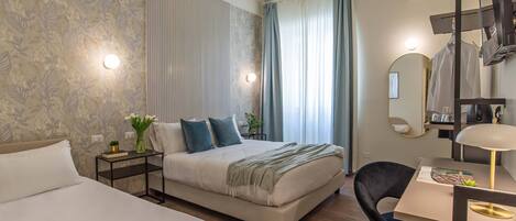 Una habitación de hotel moderna con cama, mesita de noche, sillón y escritorio con lámpara.