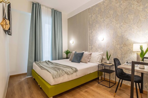 A modern bedroom with a green bed, a desk with a chair, a potted plant, and a window with curtains.