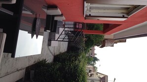Une ruelle étroite avec un mur rouge et une porte blanche.
