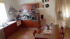 Une cuisine avec des meubles de rangement en bois, une cuisinière, un four, un four à micro-ondes et un évier. On y trouve également une table à manger avec des chaises et un vase décoratif.