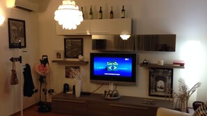 Un salon doté d’un téléviseur à écran plat, d’un lustre, d’une cheminée et d’un meuble à vin.