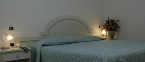 Ein Schlafzimmer mit einem Bett, Nachttischlampen, einem Beistelltisch und einer Wandleuchte.