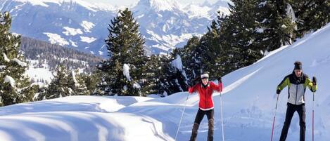 Two skiers on a snowy slope with a mountainous backdrop.