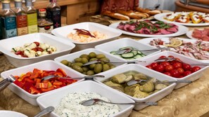 Een buffet met diverse gerechtjes, waaronder olijven, kerstomaatjes en een romige dip.