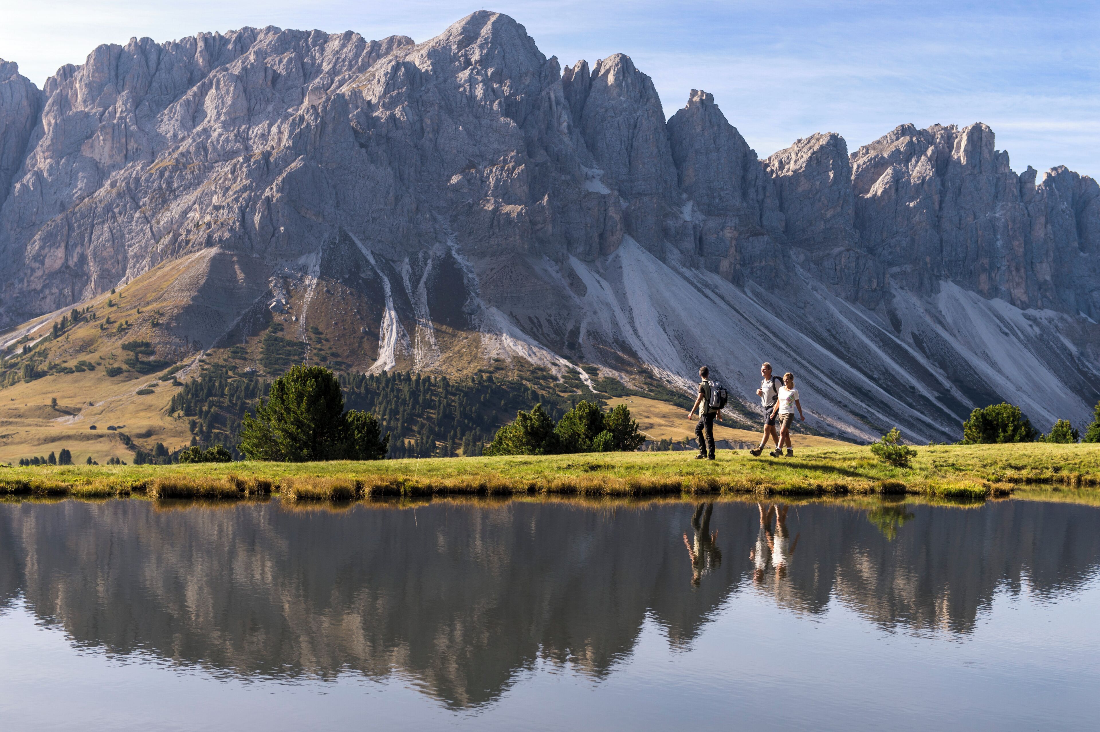 Un paysage montagneux avec un lac aux eaux miroitantes, un terrain rocheux et quelques randonneurs.