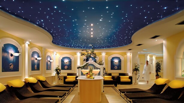 Ein Spa mit Sternenhimmel, gelb-schwarzen Sitzgelegenheiten und einer zentralen Rezeption.