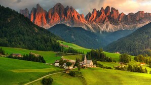 Eine gebirgige Landschaft mit einem Dorf, Häusern und einer Kirche.