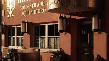 Een hotel met een bord waarop staat 'HOTEL GOLDENER ADLER BAR AQUILA D'ORO' en een bakstenen gevel.