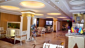 Una zona de recepción con mostrador, sillas, televisor y banderas.