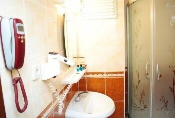 Une salle de bain équipée de toilettes, d’un sèche-mains et d’un téléphone fixé au mur.