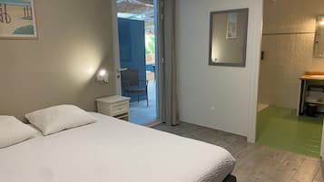 A bedroom with a bed, a nightstand, a chair, and a bathroom visible through an open door.