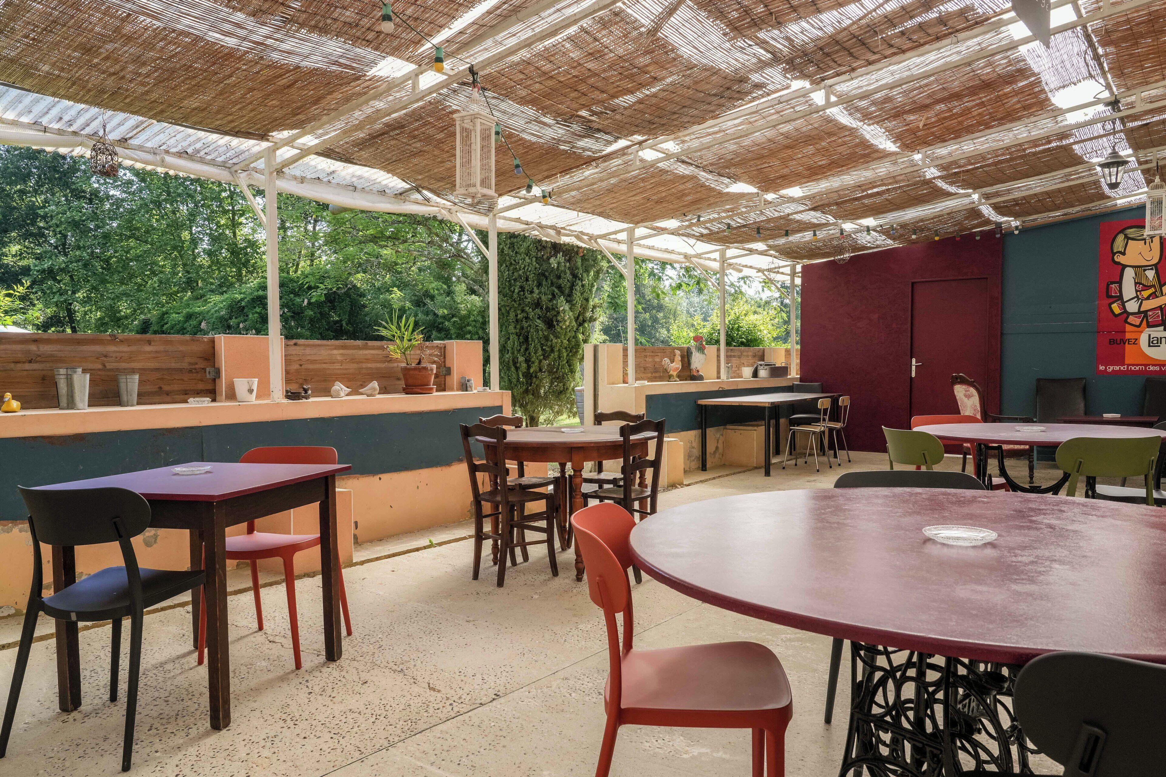 An outdoor patio area with tables and chairs, a wooden counter, and a mural on the wall.