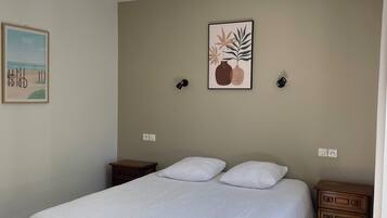 A bedroom with a bed, two bedside tables, a nightstand, a dresser, and two wall-mounted lamps.