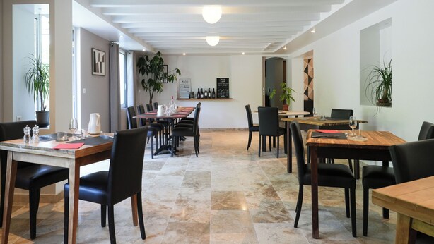 A spacious dining area with multiple tables and chairs, a coffee machine, and potted plants.