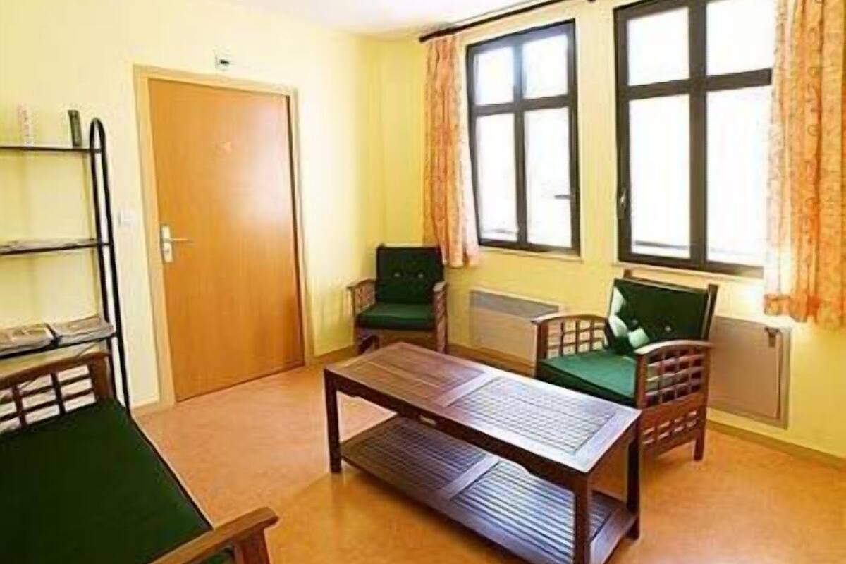 A room with a wooden table, two chairs, a bookshelf, and a door.