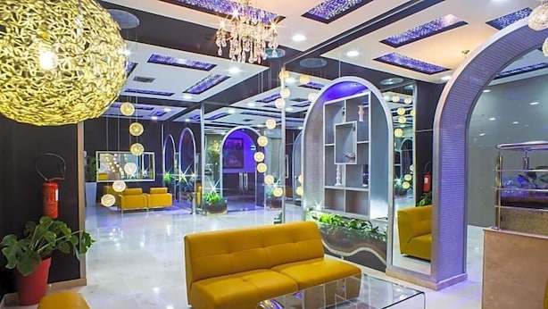 A modern lobby with a yellow sofa, glass coffee table, and decorative lighting. - Tanjah Flandria (Tangier)