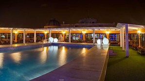 A swimming pool with a covered area, lounge chairs, and a dome structure in the background. - Tanjah Flandria (Tangier)