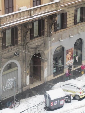 A building with a closed garage door, a bicycle parked outside, and a snow-covered street. - San Giovanni in Laterano (Rome)