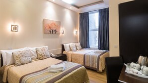 A hotel room with two beds, a painting of roses, a window with curtains, a coffee maker, and a tray with cups and a plate. - Notting Hill Gate Hotel (London)