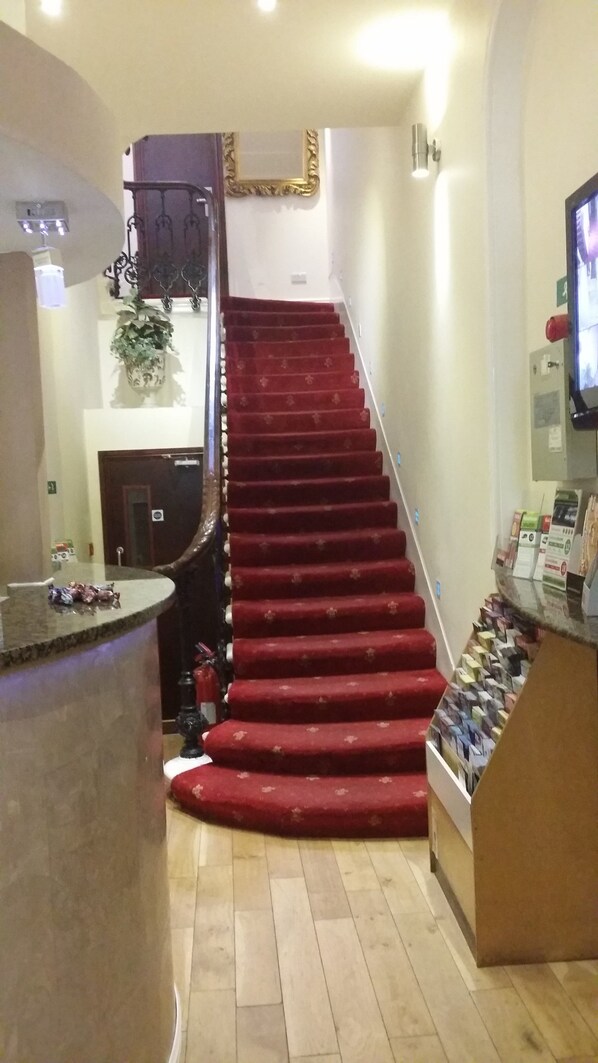 A staircase with red carpeted steps leading to a landing. - Notting Hill Gate Hotel (London)