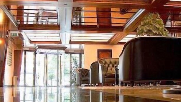 A spacious lobby with a reflective floor, large windows, and a reception desk.