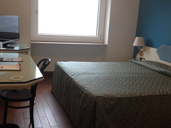 Una habitación pequeña y sencilla con una cama, un escritorio y una silla.