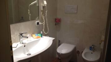Un baño con lavamanos, inodoro, bidé y espejo.