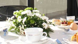 A table set for a meal with white plates, cups, and a floral centerpiece.