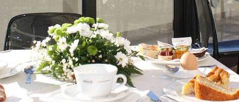 A table set for a meal with white plates, cups, and a floral centerpiece.