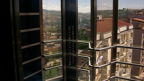 An elevator with a view of a cityscape through large windows.