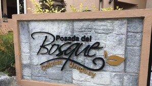 A stone sign with the text "Posada del Bosque" and "Colonia Uruguay" indicating a location or establishment. - Posada del Bosque (Colonia del Sacramento)