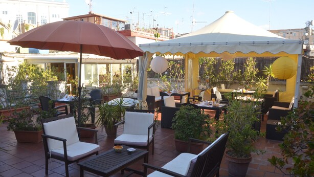 An outdoor patio with multiple seating areas, including chairs and tables, surrounded by potted plants. - BB Soriano 44 (Naples)
